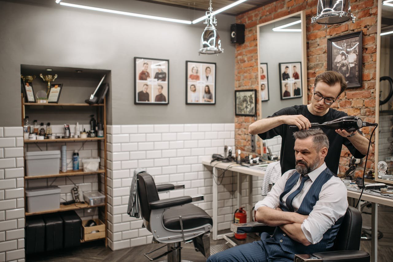 Home A barber styling a customers hair in a modern, stylish barbershop setting.
