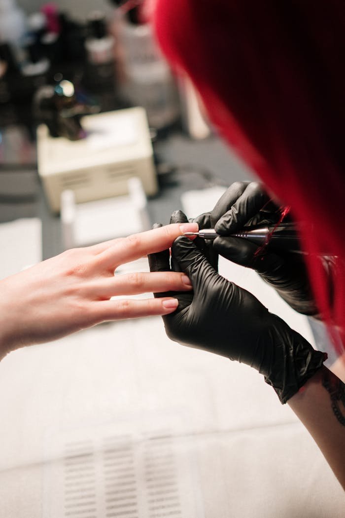 Manicure session with technician wearing black gloves applying nail polish in a salon.