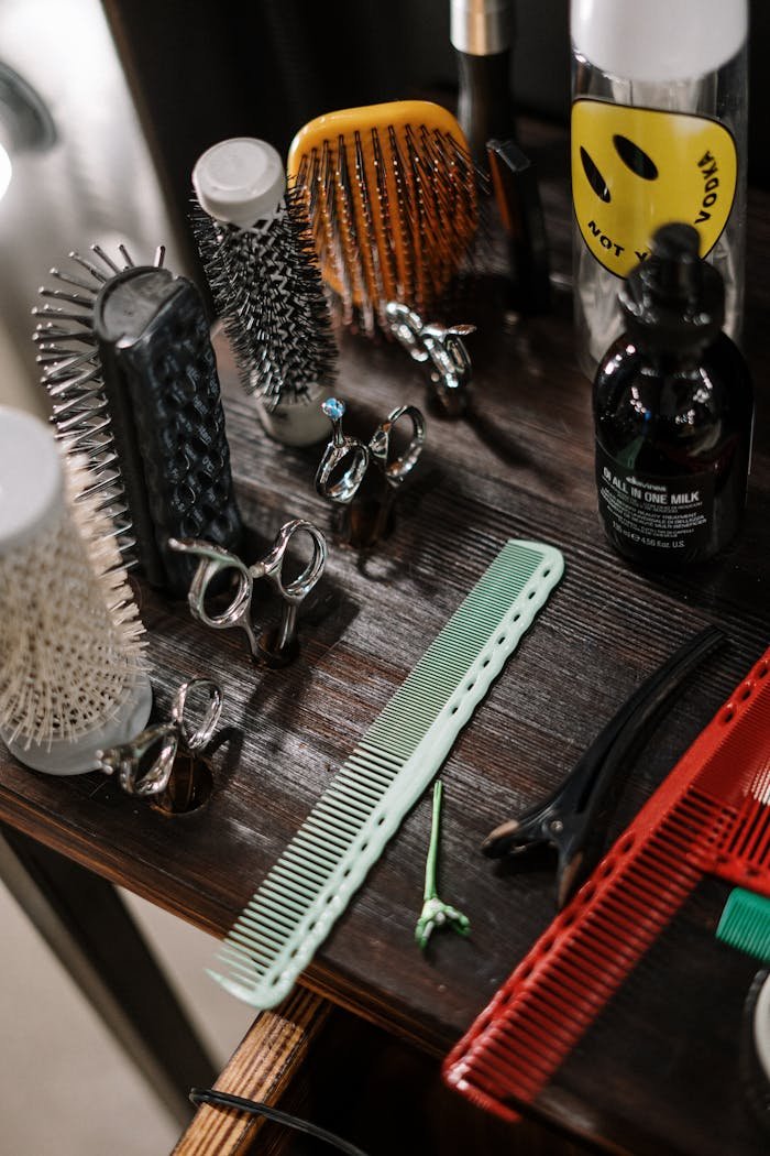 Home Close-up of diverse barber tools and styling products arranged on a wooden table in a salon.